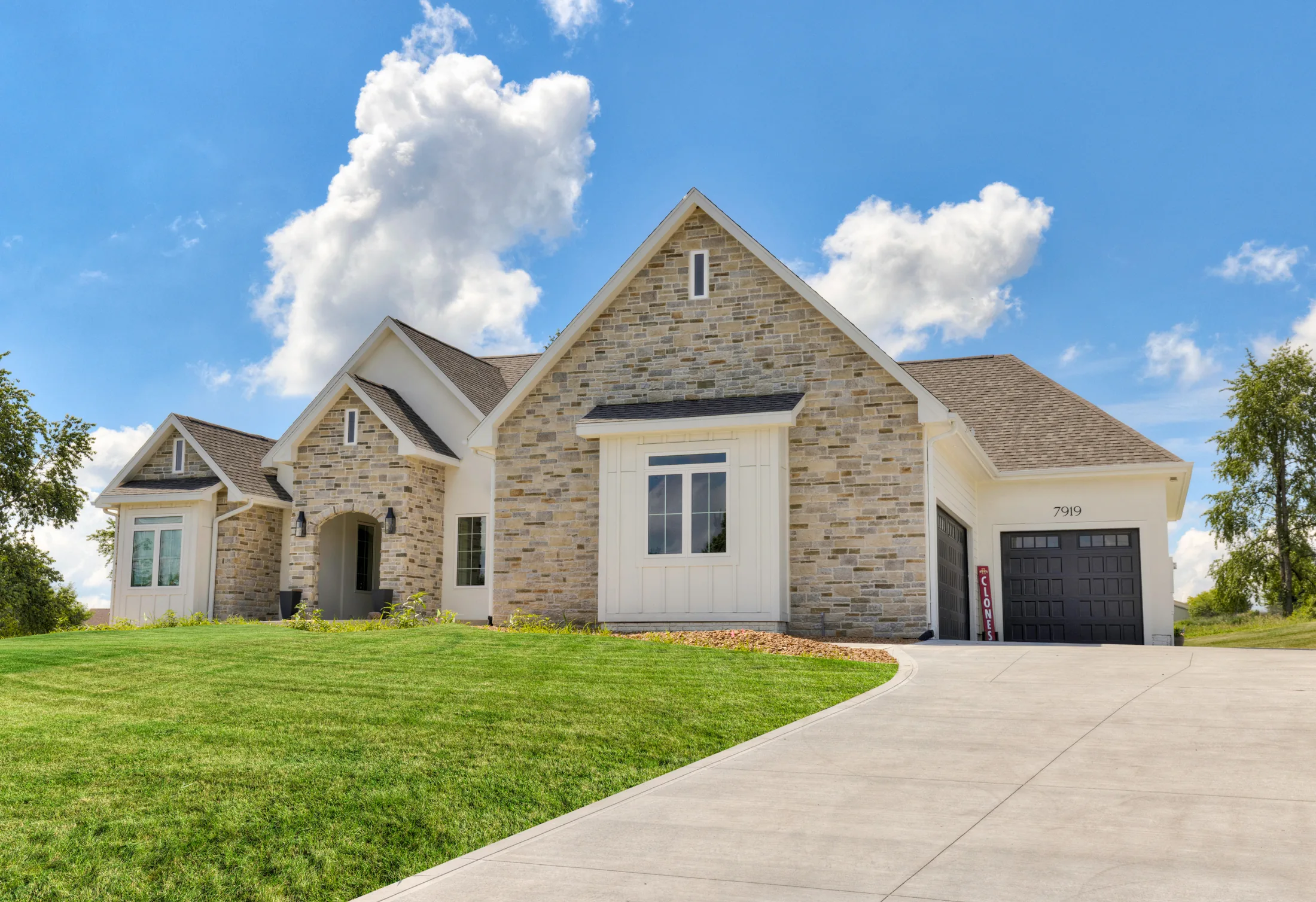Front exterior of the 7919 SE 6th Ave custom home in Runnells, Iowa, with stone and stucco facade and three-car garage